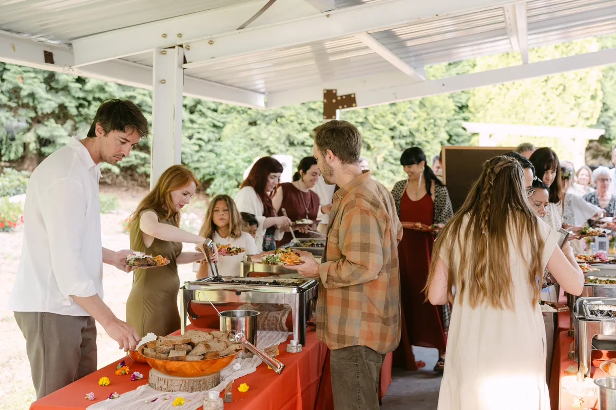 Guests moving along a long Kinship buffet under an open pavilion