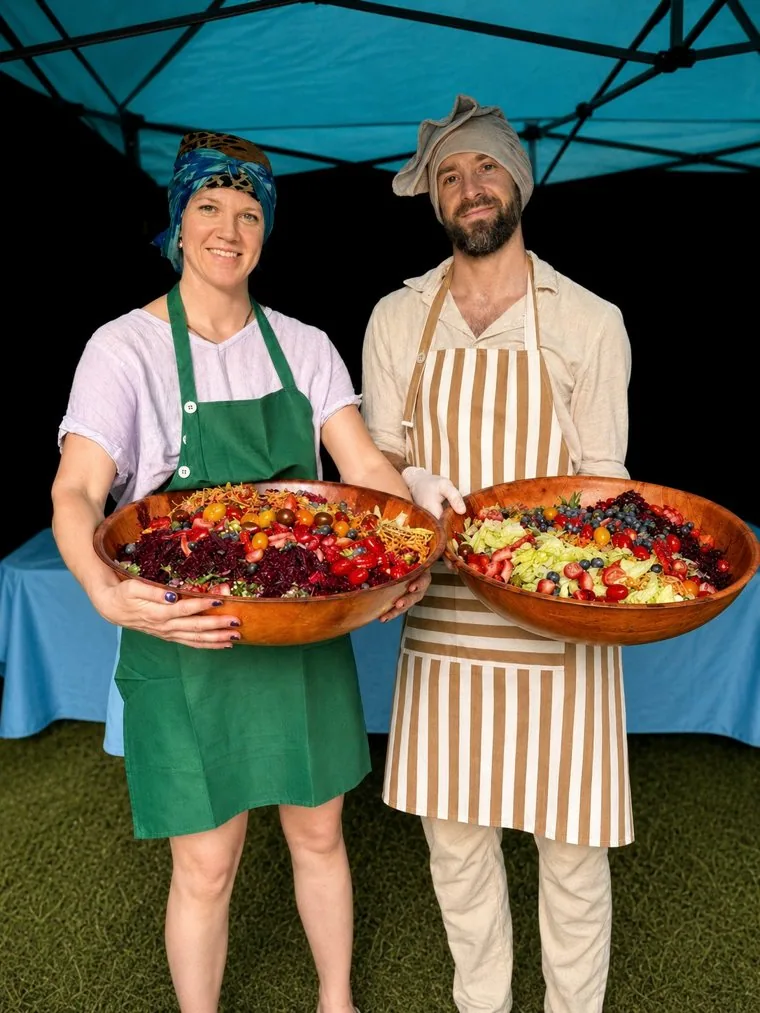 Two of the team holding large bowls of prepared food