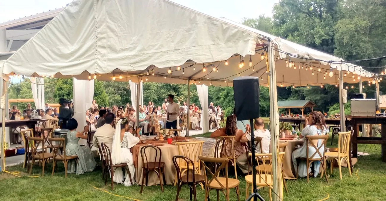 An outdoor tented wedding reception with string lights